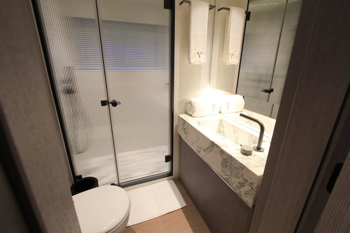 A modern yacht bathroom featuring a sleek sink and a glass-enclosed shower. aboard OASIS 34M BO212 Yacht for Sale