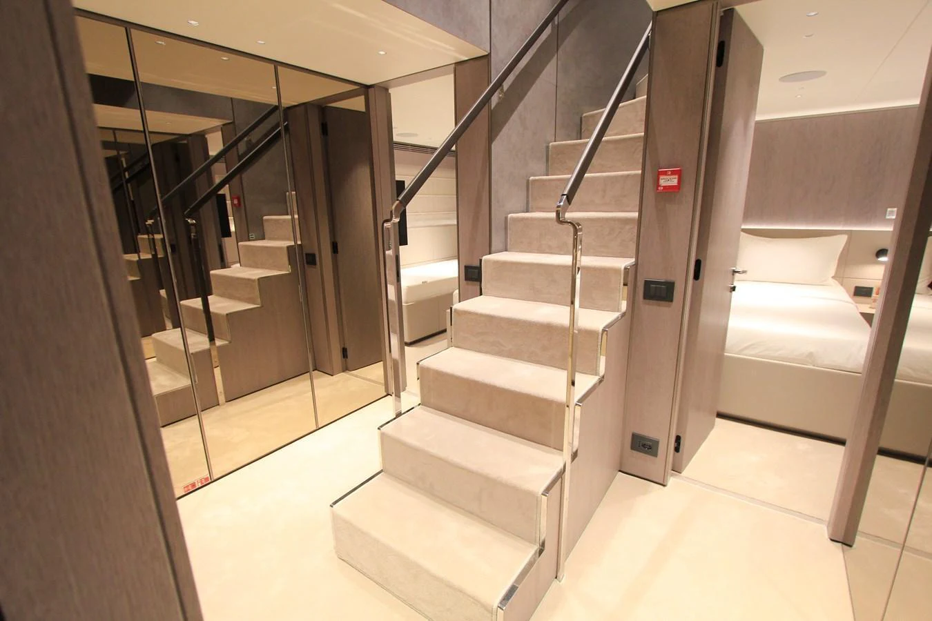 A luxurious interior staircase with mirrored walls and plush carpeting leads to the upper deck. aboard OASIS 34M BO212 Yacht for Sale