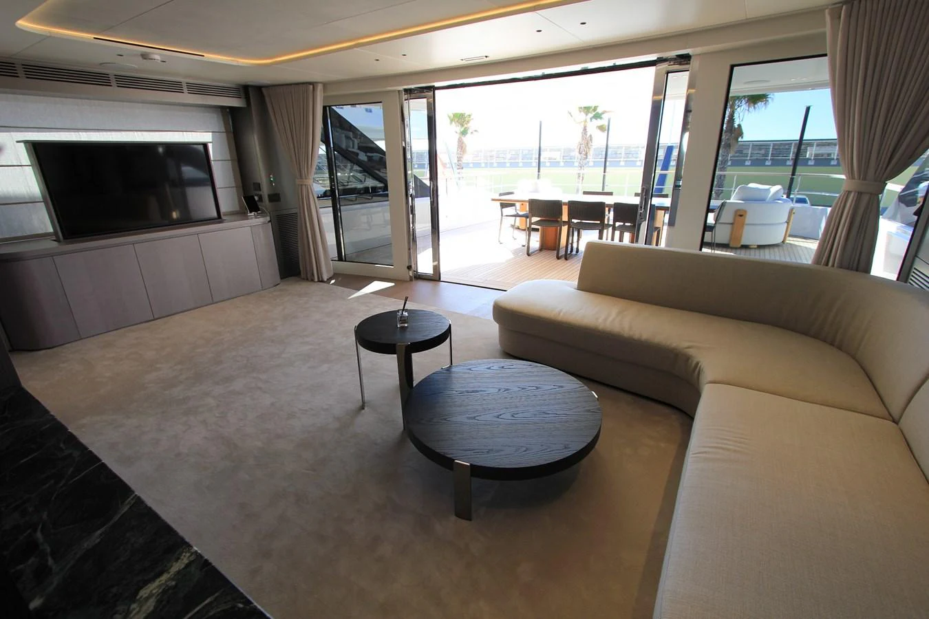 The spacious salon features a large, comfortable sofa and modern entertainment system, opening to an inviting outdoor deck area. aboard OASIS 34M BO212 Yacht for Sale