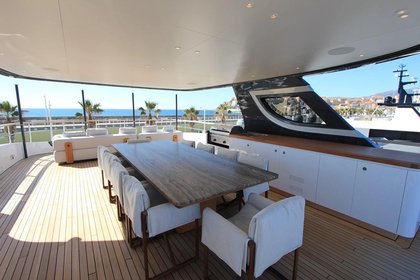 The aft deck features a spacious dining area with a large table and comfortable seating, perfect for alfresco dining with a view. aboard OASIS 34M BO212 Yacht for Sale