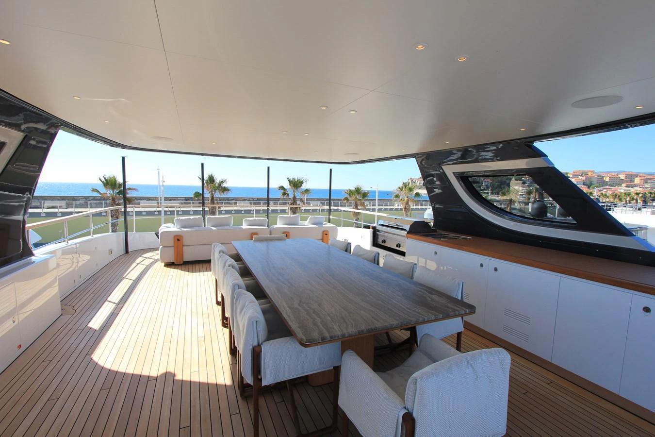 The aft deck features a spacious dining area with a large table and comfortable seating, perfect for alfresco meals with a view. aboard OASIS 34M BO212 Yacht for Sale