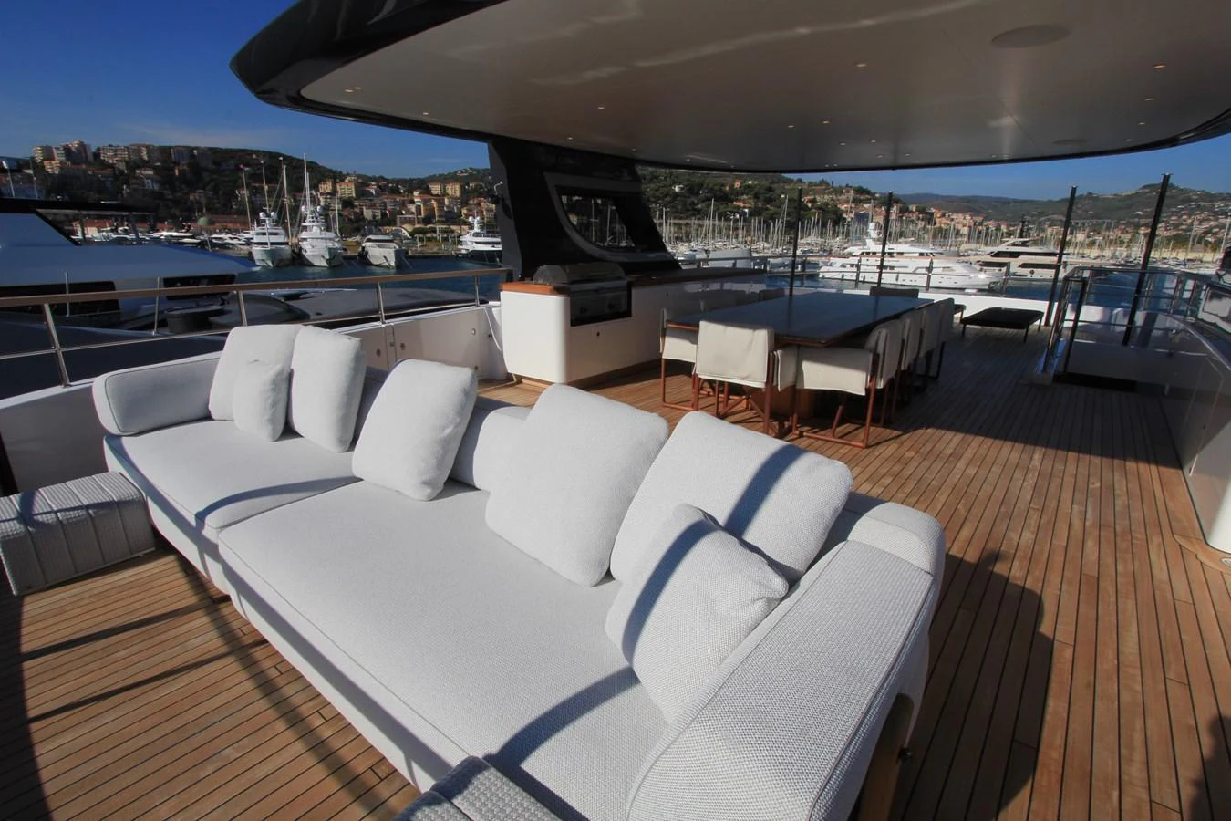 The aft deck features a spacious lounging area with plush white seating and a dining table, perfect for enjoying the marina views. aboard OASIS 34M BO212 Yacht for Sale