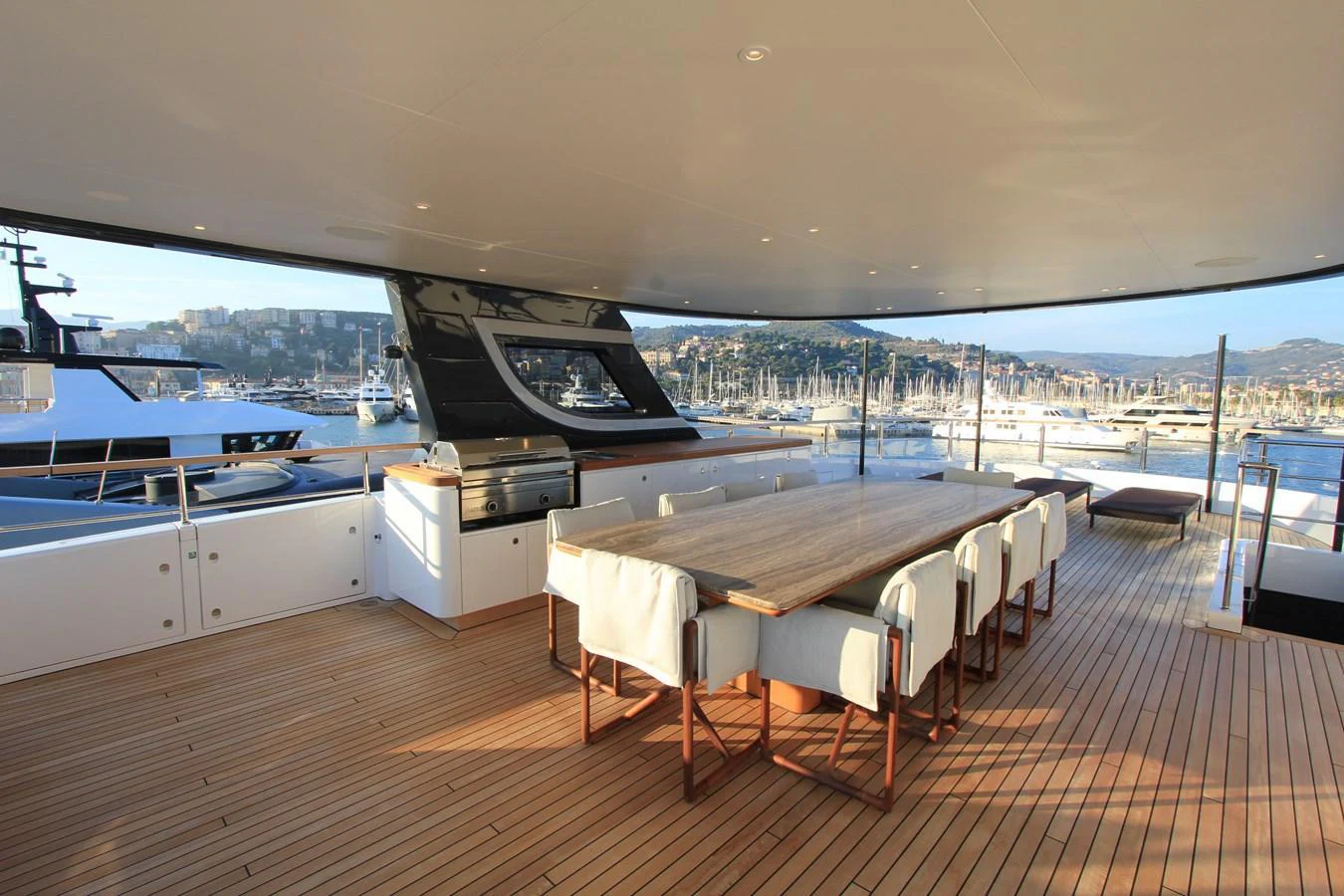 The aft deck features a spacious dining area with a large table and comfortable seating, perfect for enjoying meals with a view of the marina. aboard OASIS 34M BO212 Yacht for Sale