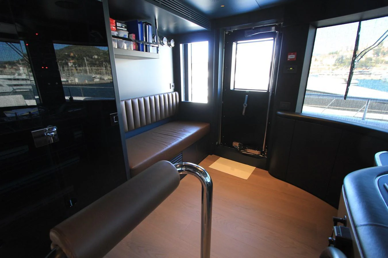 The image showcases a modern interior space with a seating area and a door leading to the exterior deck. aboard OASIS 34M BO212 Yacht for Sale