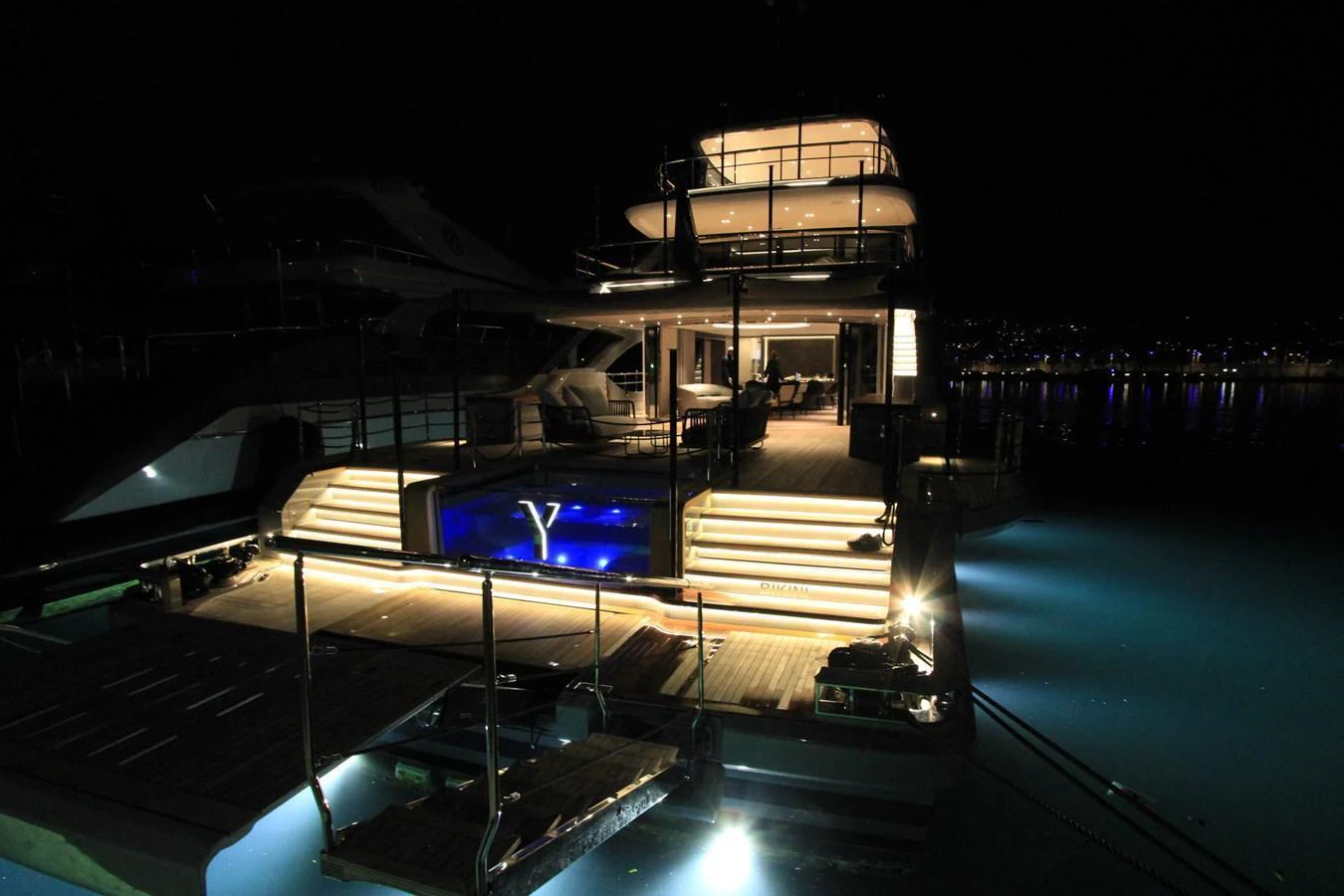 The yacht's aft deck is beautifully illuminated at night, showcasing a luxurious pool and inviting ambiance. aboard OASIS 34M BO212 Yacht for Sale