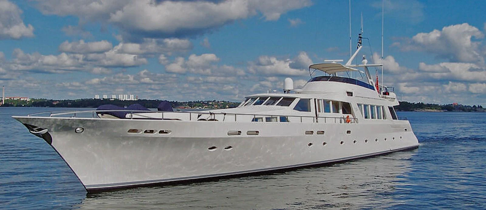 A sleek and elegant yacht cruising on calm waters under a partly cloudy sky. aboard UNITED SPIRIT Yacht for Sale