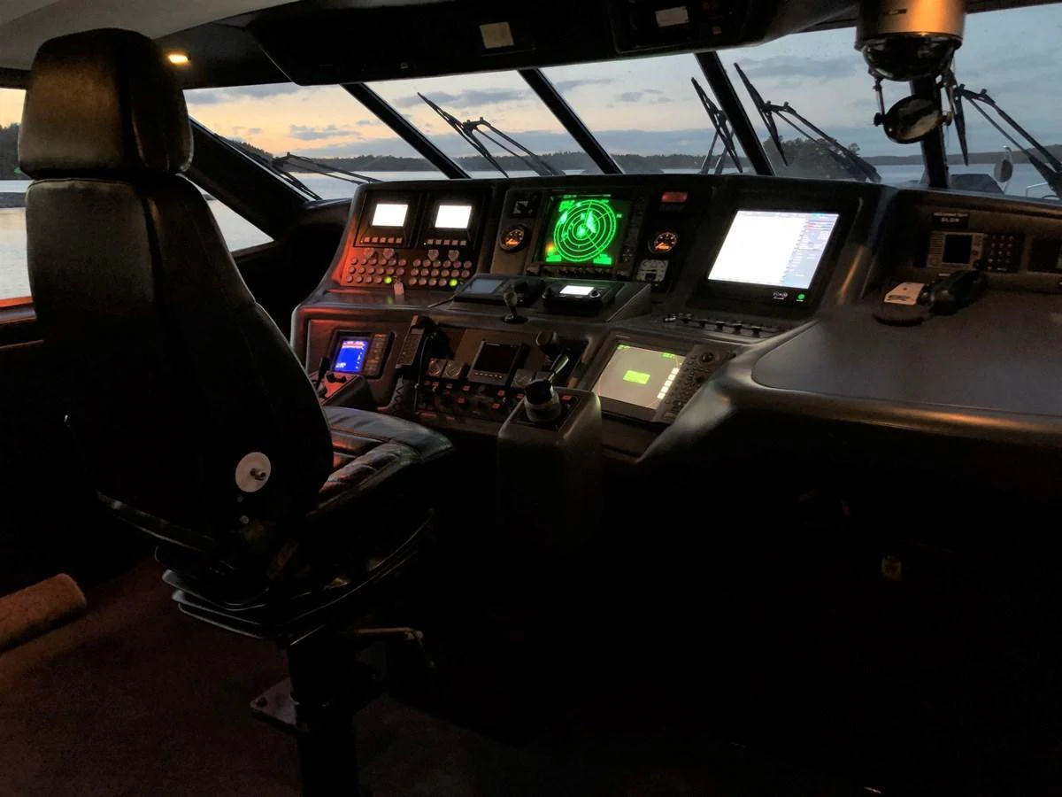 The helm station features advanced navigation equipment and a comfortable captain's chair, set against a backdrop of a serene sunset. aboard UNITED SPIRIT Yacht for Sale