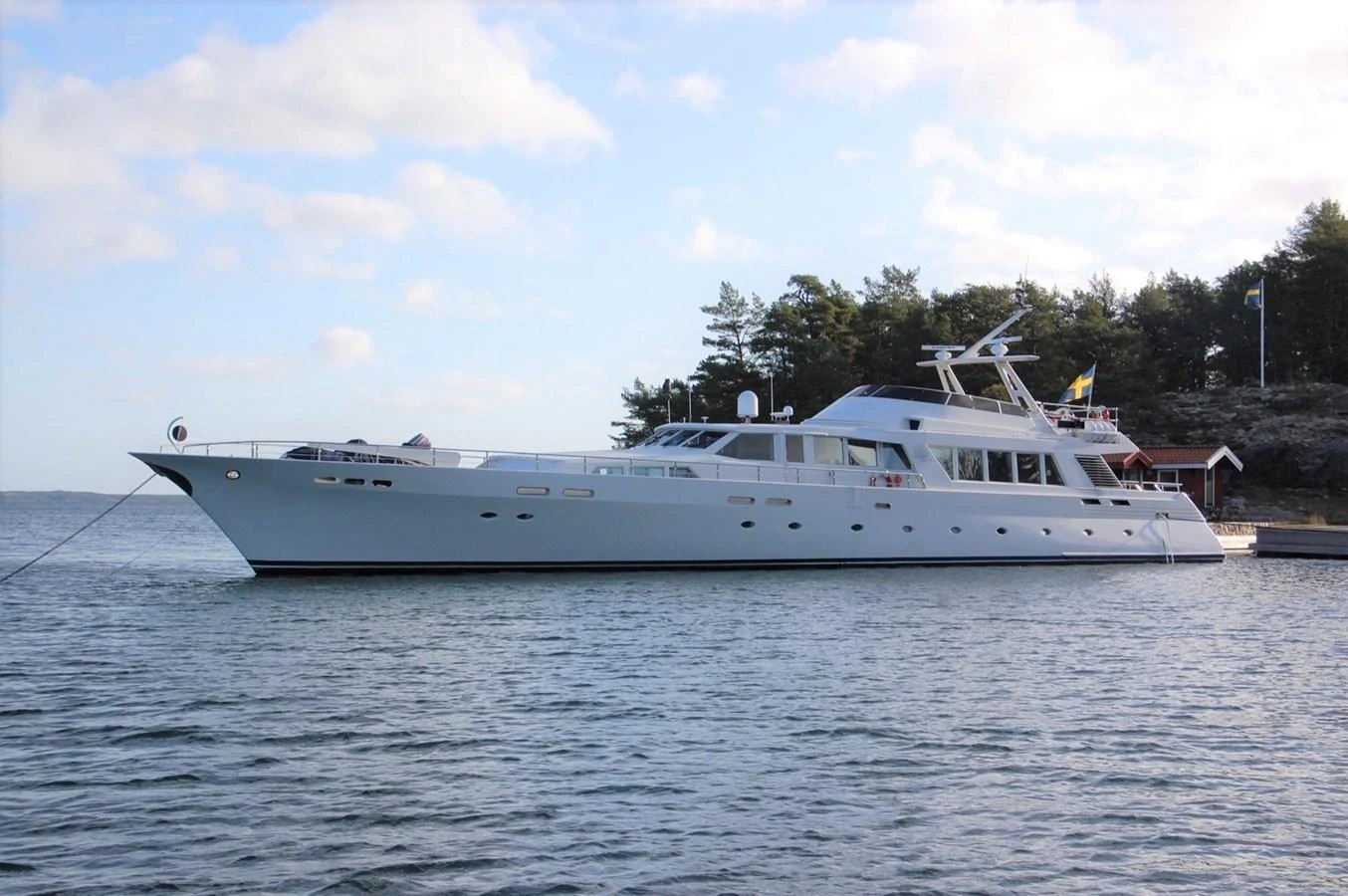 A sleek and elegant yacht is docked in a serene waterside setting. aboard UNITED SPIRIT Yacht for Sale
