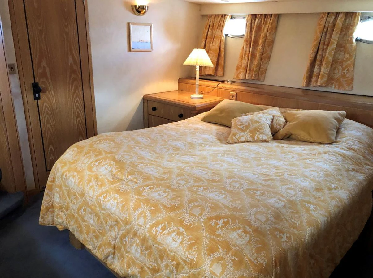A cozy stateroom featuring a comfortable bed with patterned bedding and warm lighting. aboard UNITED SPIRIT Yacht for Sale