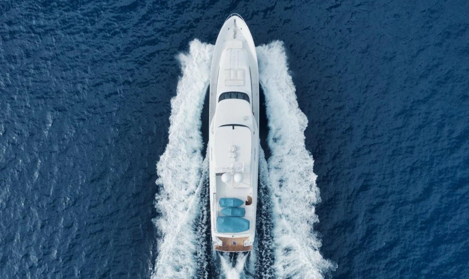 Aerial view of a yacht cruising through the open sea, leaving a trail of white waves behind. aboard ISLAND GIRL Yacht for Sale