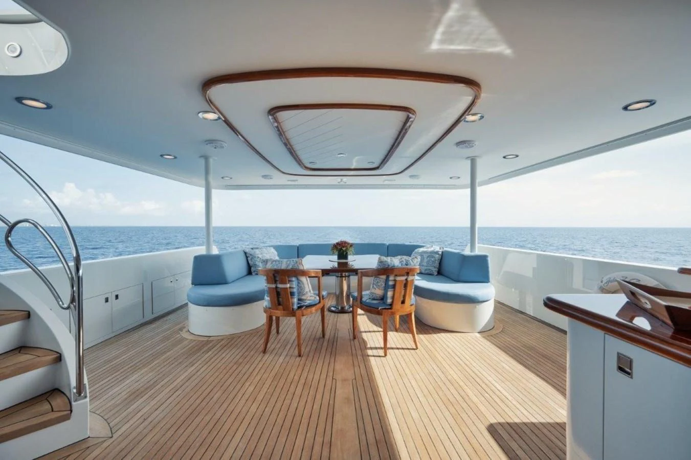 The aft deck features a spacious seating area with a wooden table and comfortable chairs, perfect for enjoying the ocean views. aboard ISLAND GIRL Yacht for Sale
