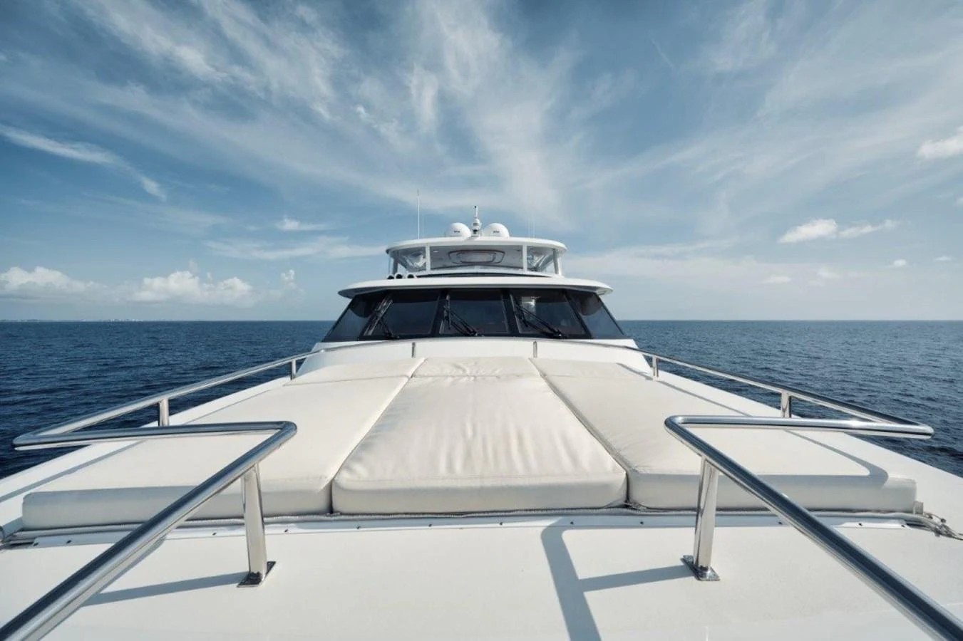 The yacht's bow offers a spacious sunbathing area with plush cushions, set against a serene ocean backdrop. aboard ISLAND GIRL Yacht for Sale