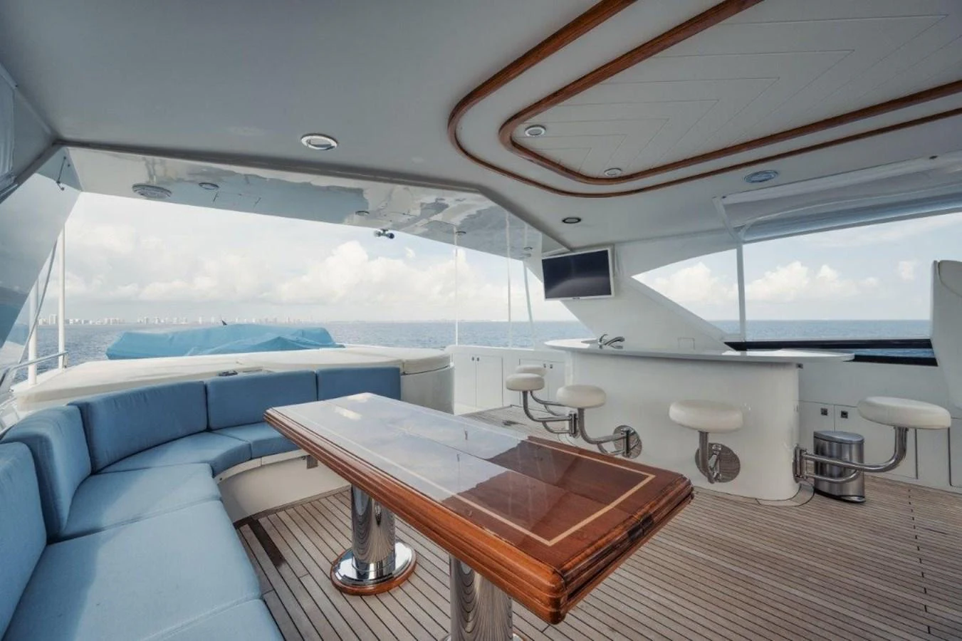 The flybridge offers a spacious seating area with a wooden table and a bar with stools, perfect for enjoying the ocean views. aboard ISLAND GIRL Yacht for Sale