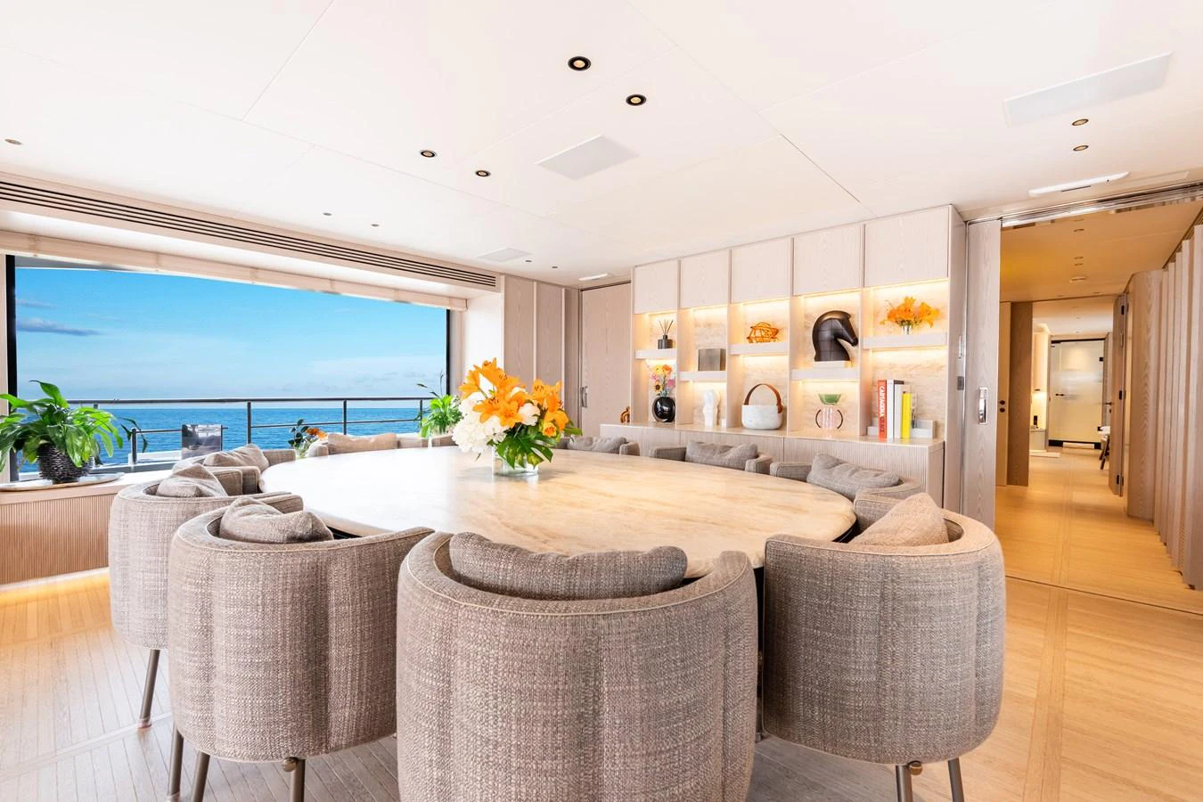 The yacht's dining area features a large round table surrounded by plush chairs, with a stunning ocean view through expansive windows. aboard A+ Yacht for Sale