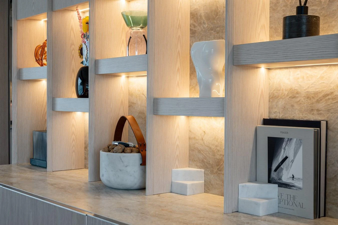 A stylishly illuminated shelf displaying decorative items and books enhances the yacht's interior elegance. aboard A+ Yacht for Sale