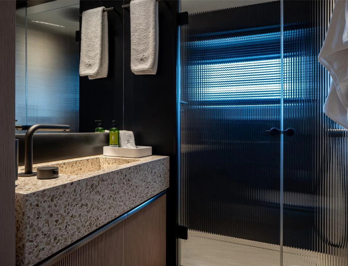 A modern yacht bathroom featuring a sleek sink and a glass-enclosed shower area. aboard A+ Yacht for Sale