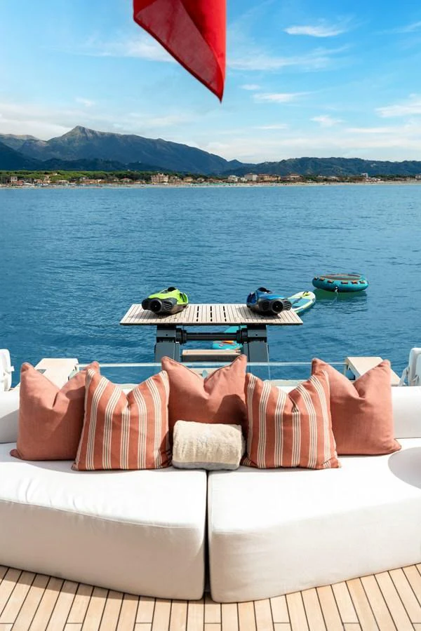 The aft deck features a comfortable seating area with a scenic view of the water and mountains. aboard A+ Yacht for Sale