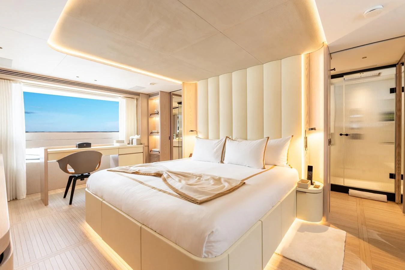 The master stateroom features a luxurious bed, elegant lighting, and a scenic ocean view through a large window. aboard A+ Yacht for Sale
