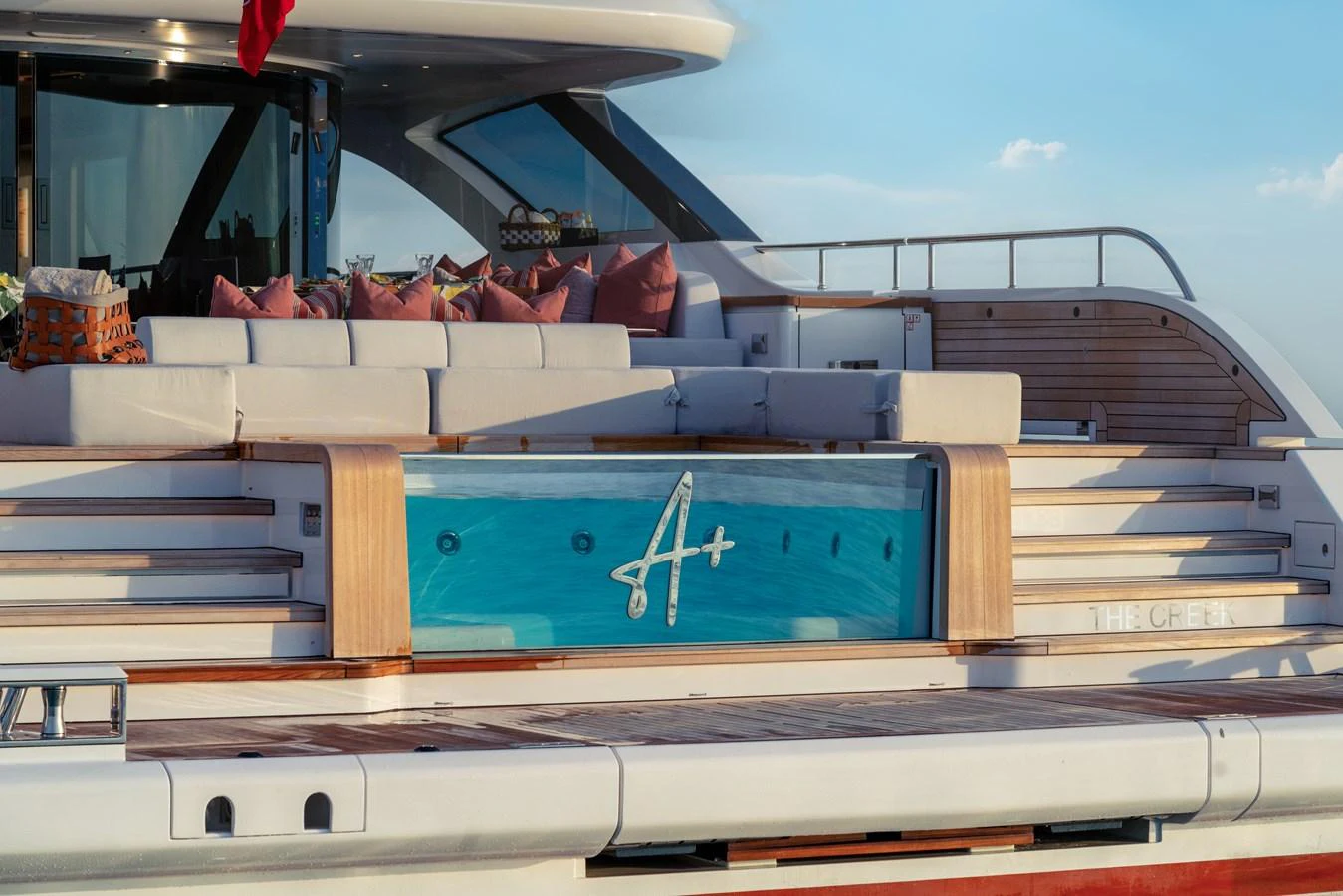 The aft deck of the yacht features a stylish seating area with plush cushions and a glass panel showcasing the yacht's name. aboard A+ Yacht for Sale