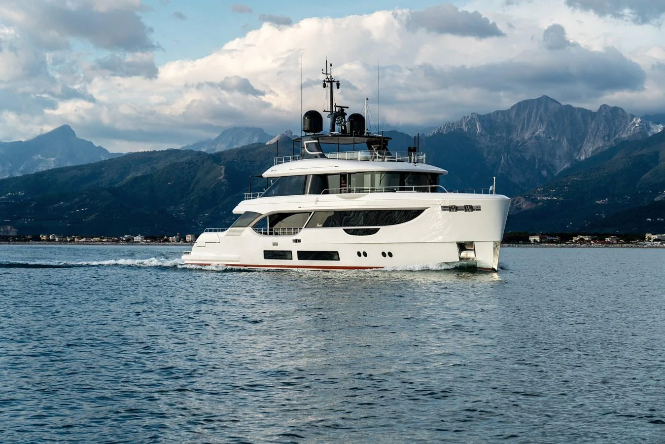 A sleek and modern yacht cruises gracefully on calm waters with a mountainous backdrop. aboard A+ Yacht for Sale