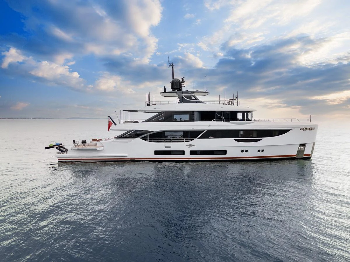 A sleek, modern yacht cruising on calm waters under a partly cloudy sky. aboard A+ Yacht for Sale