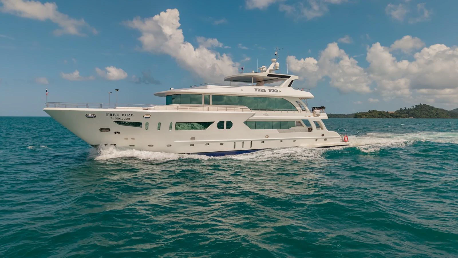 A luxurious yacht cruises through clear blue waters under a bright sky. aboard FREE BIRD Yacht for Sale