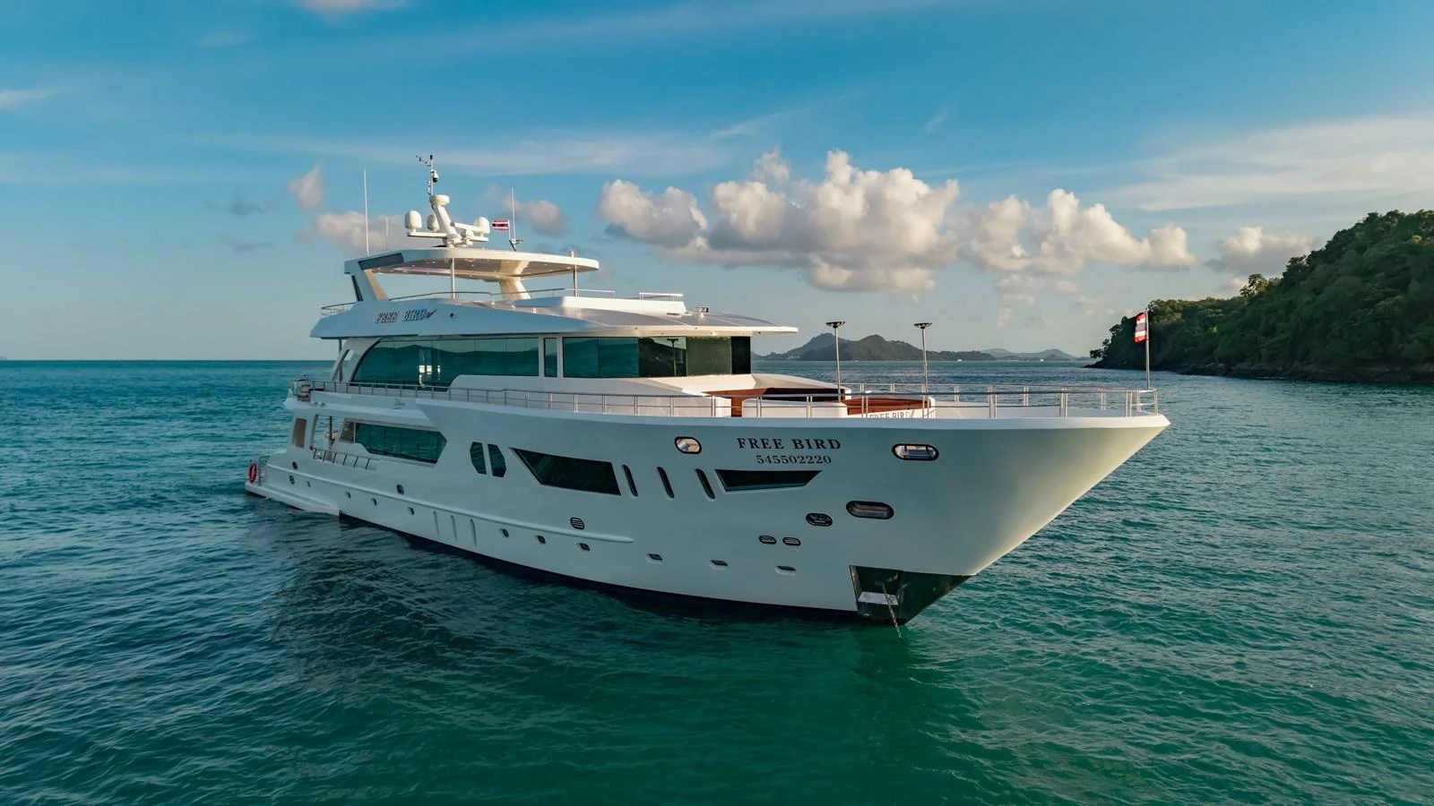 A luxurious yacht glides gracefully on calm waters under a clear blue sky. aboard FREE BIRD Yacht for Sale