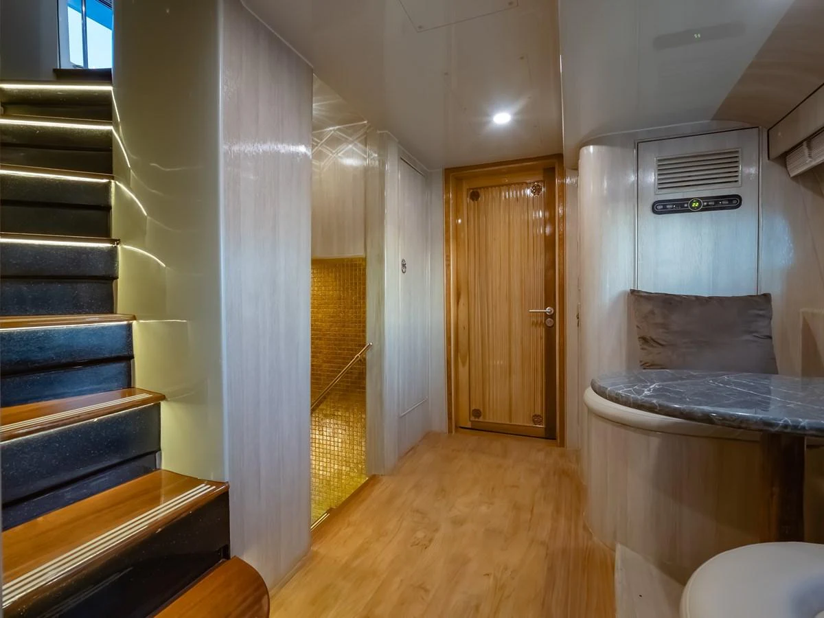 A cozy interior space featuring a staircase, a wooden door, and a small seating area with a table. aboard FREE BIRD Yacht for Sale