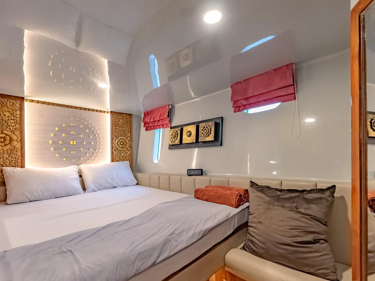 The stateroom features a cozy bed with elegant decor and soft lighting. aboard FREE BIRD Yacht for Sale