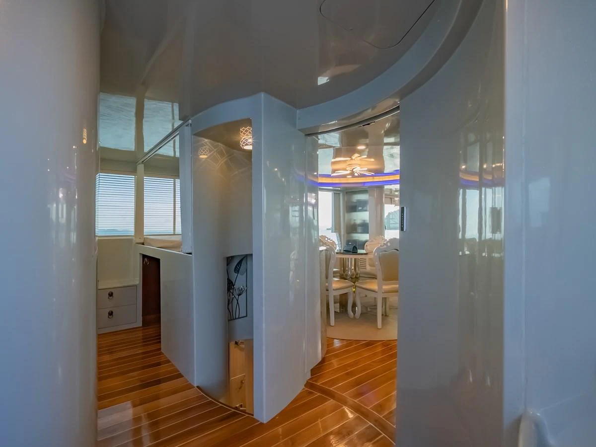 The image showcases a sleek and modern interior space with polished wooden floors and a dining area in the background. aboard FREE BIRD Yacht for Sale
