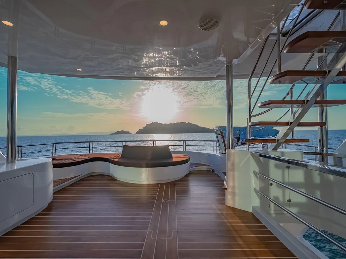 The aft deck offers a serene view of the ocean with elegant seating and a stylish staircase. aboard FREE BIRD Yacht for Sale