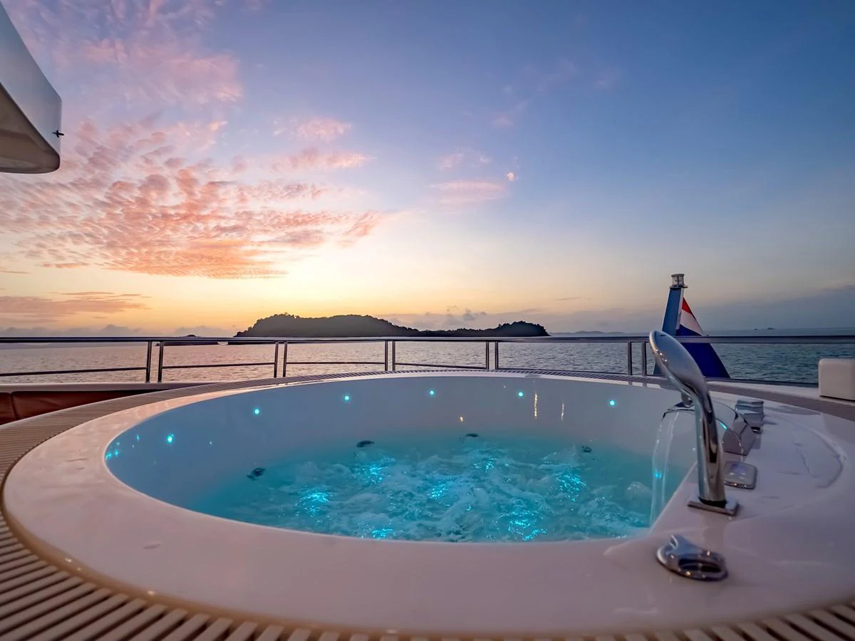 The yacht features a luxurious jacuzzi on the deck with a stunning sunset view over the water. aboard FREE BIRD Yacht for Sale