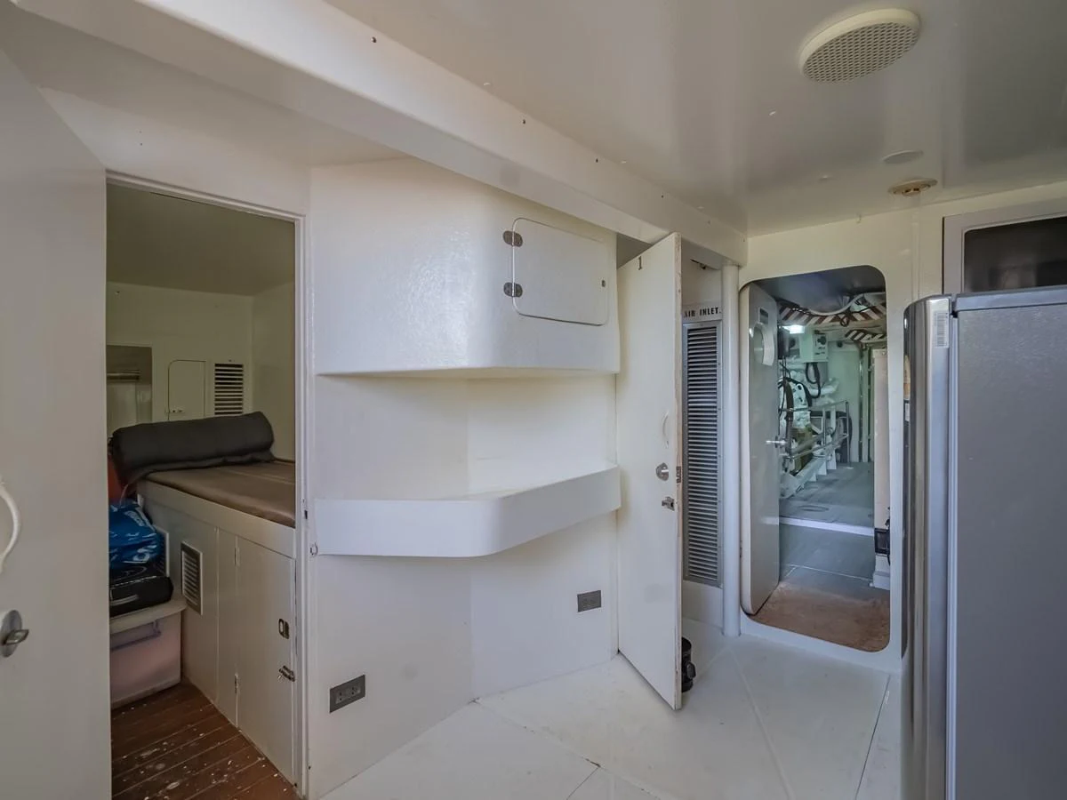 The image showcases a functional interior space with access to an engine room and a small sleeping area. aboard FREE BIRD Yacht for Sale