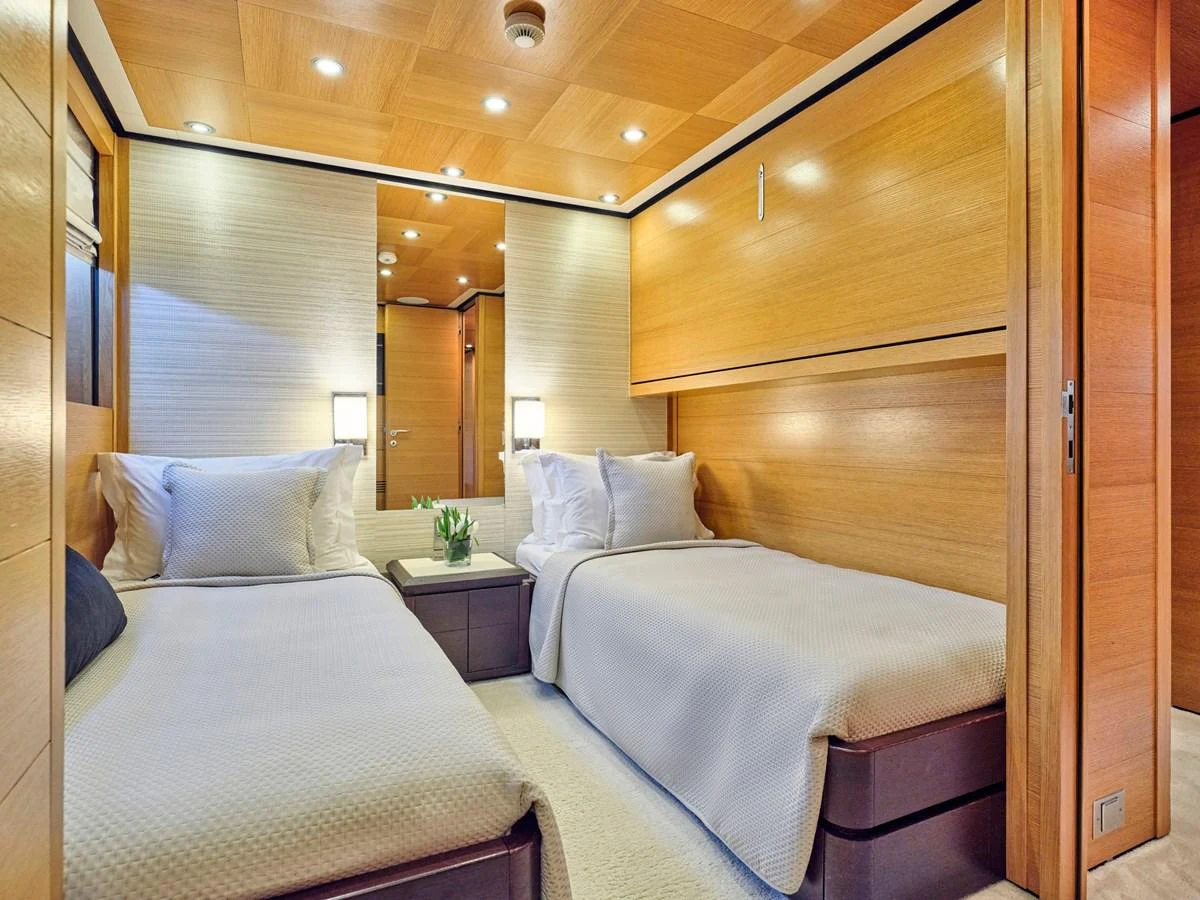 The guest stateroom features twin beds with elegant bedding and warm wooden accents. aboard VENETICO Yacht for Sale