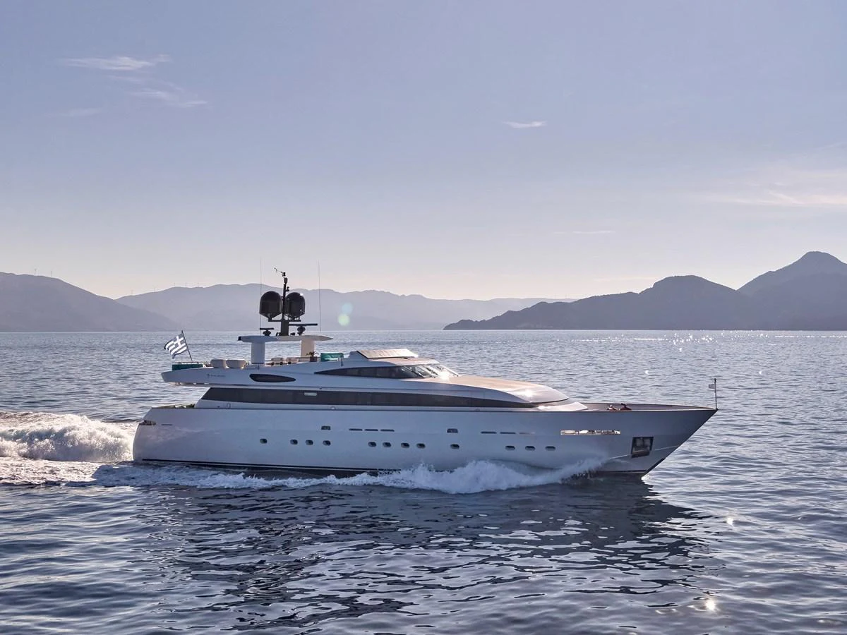 A sleek and modern yacht cruises through calm waters with a stunning mountainous backdrop. aboard VENETICO Yacht for Sale