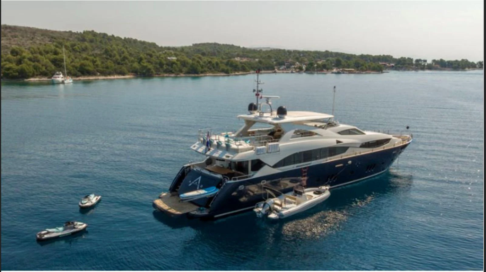 A luxurious yacht anchored in serene waters with tenders and jet skis nearby. aboard ARAGO Yacht for Sale