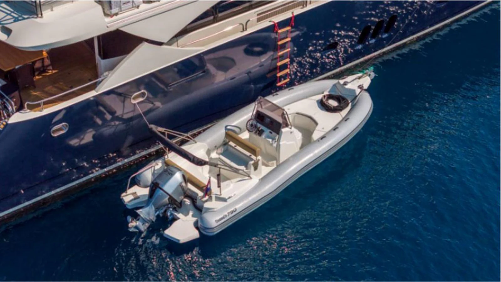 A sleek tender is docked alongside a luxurious yacht, ready for excursions. aboard ARAGO Yacht for Sale