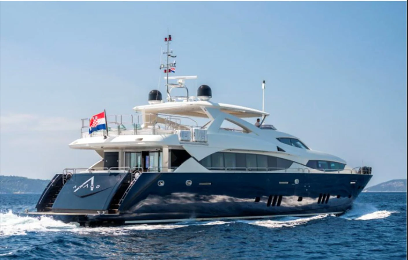 A sleek and modern yacht cruising on the open sea under a clear blue sky. aboard ARAGO Yacht for Sale