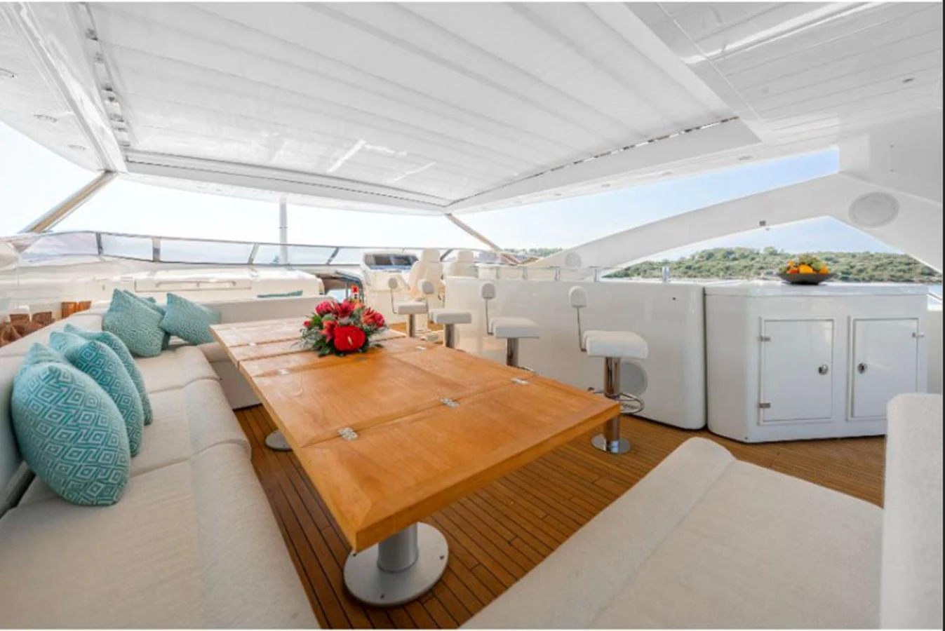 The flybridge features a spacious dining area with a wooden table and comfortable seating, perfect for alfresco dining. aboard ARAGO Yacht for Sale