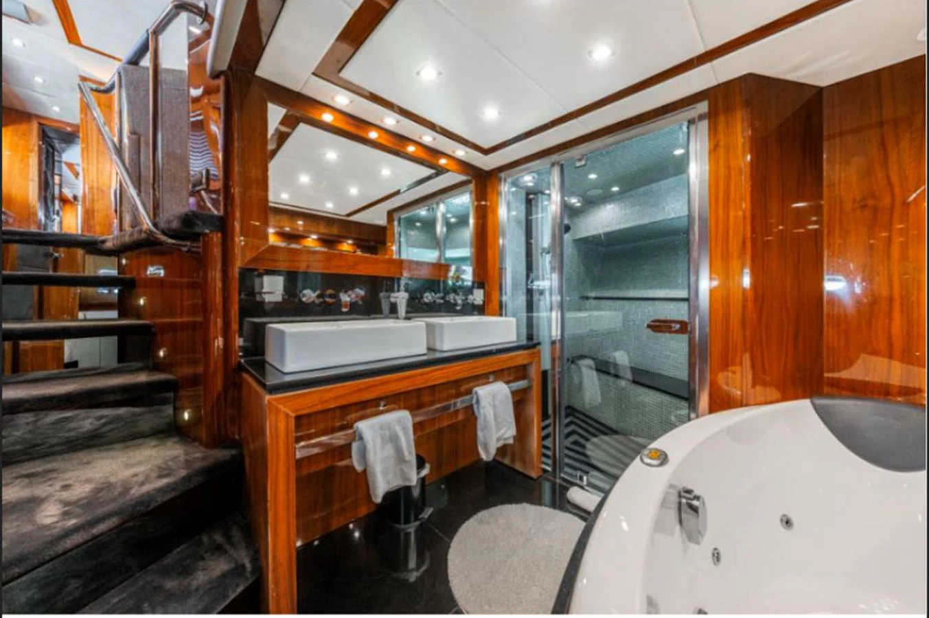 The yacht's bathroom features luxurious wood paneling, dual sinks, and a spacious jacuzzi tub. aboard ARAGO Yacht for Sale