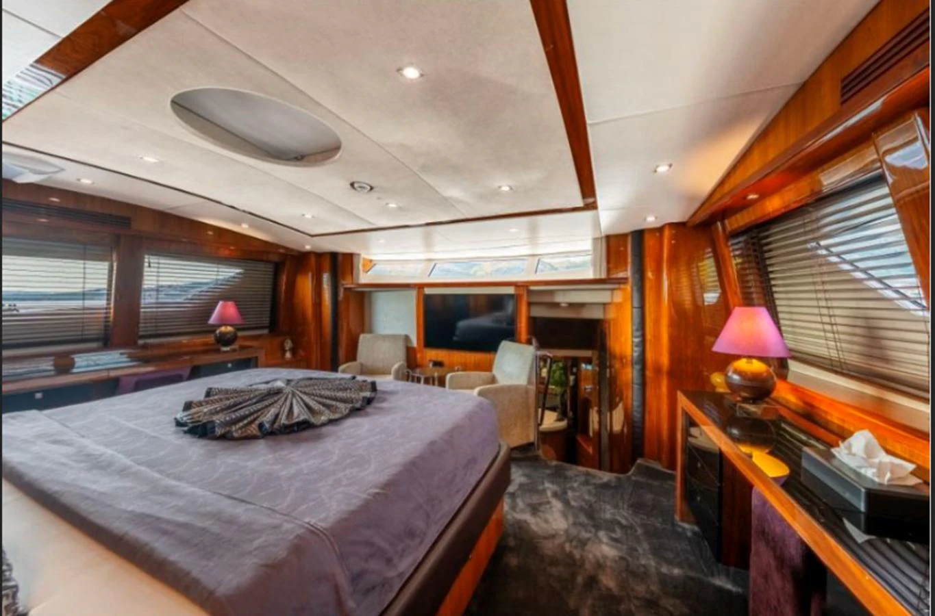 The master stateroom features a luxurious bed, elegant wood finishes, and ambient lighting. aboard ARAGO Yacht for Sale
