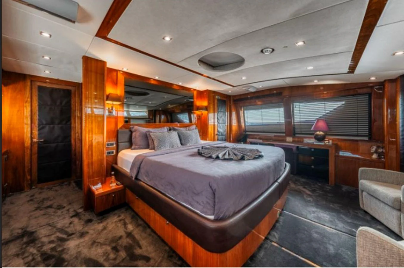 The master stateroom features a luxurious bed with elegant wood paneling and ample natural light. aboard ARAGO Yacht for Sale