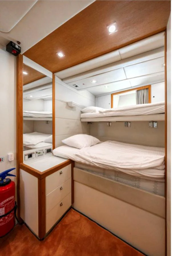The cozy bunk room features neatly arranged beds and a warm, inviting ambiance. aboard ARAGO Yacht for Sale