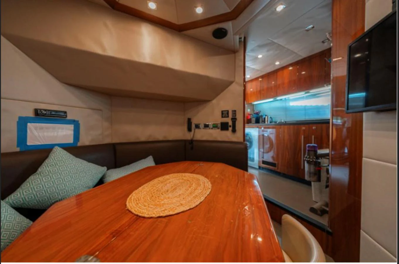 The yacht's interior features a cozy dining area with a polished wooden table and a well-equipped galley in the background. aboard ARAGO Yacht for Sale