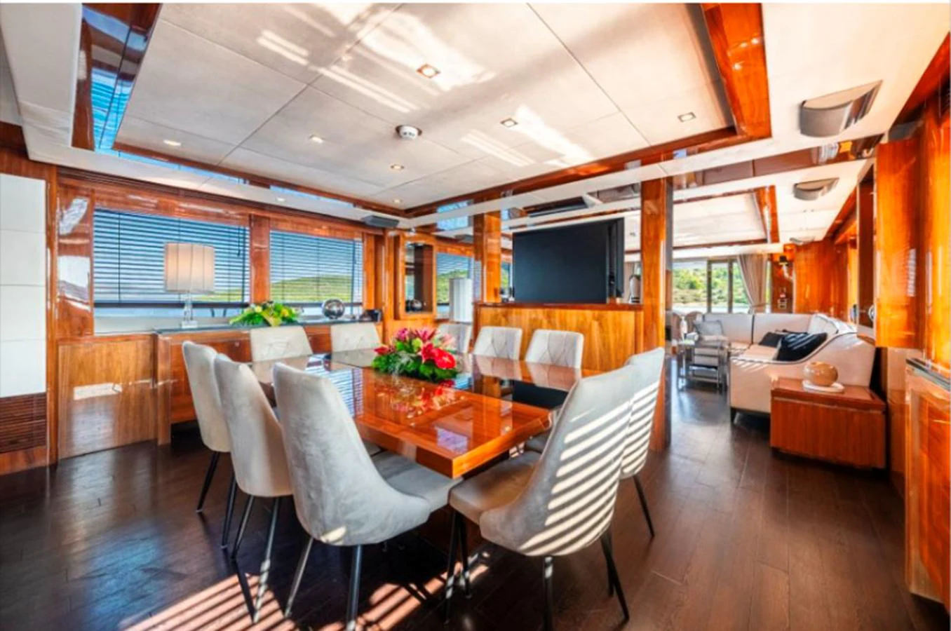 The yacht's dining area features a luxurious table surrounded by plush chairs, with ample natural light and elegant wood finishes. aboard ARAGO Yacht for Sale