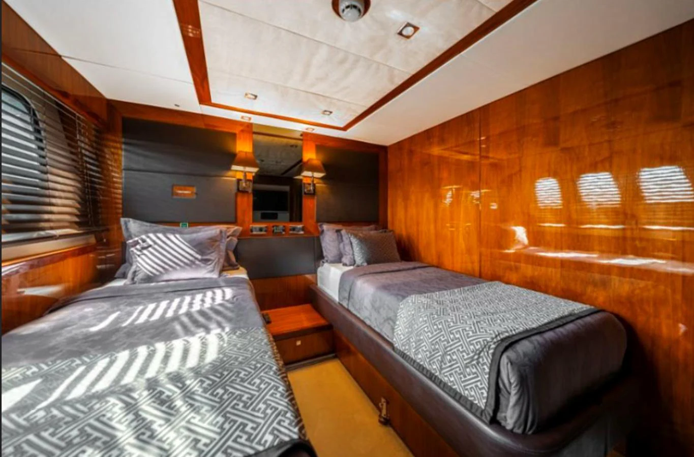 The twin stateroom features two comfortable single beds with elegant bedding and warm wood paneling. aboard ARAGO Yacht for Sale