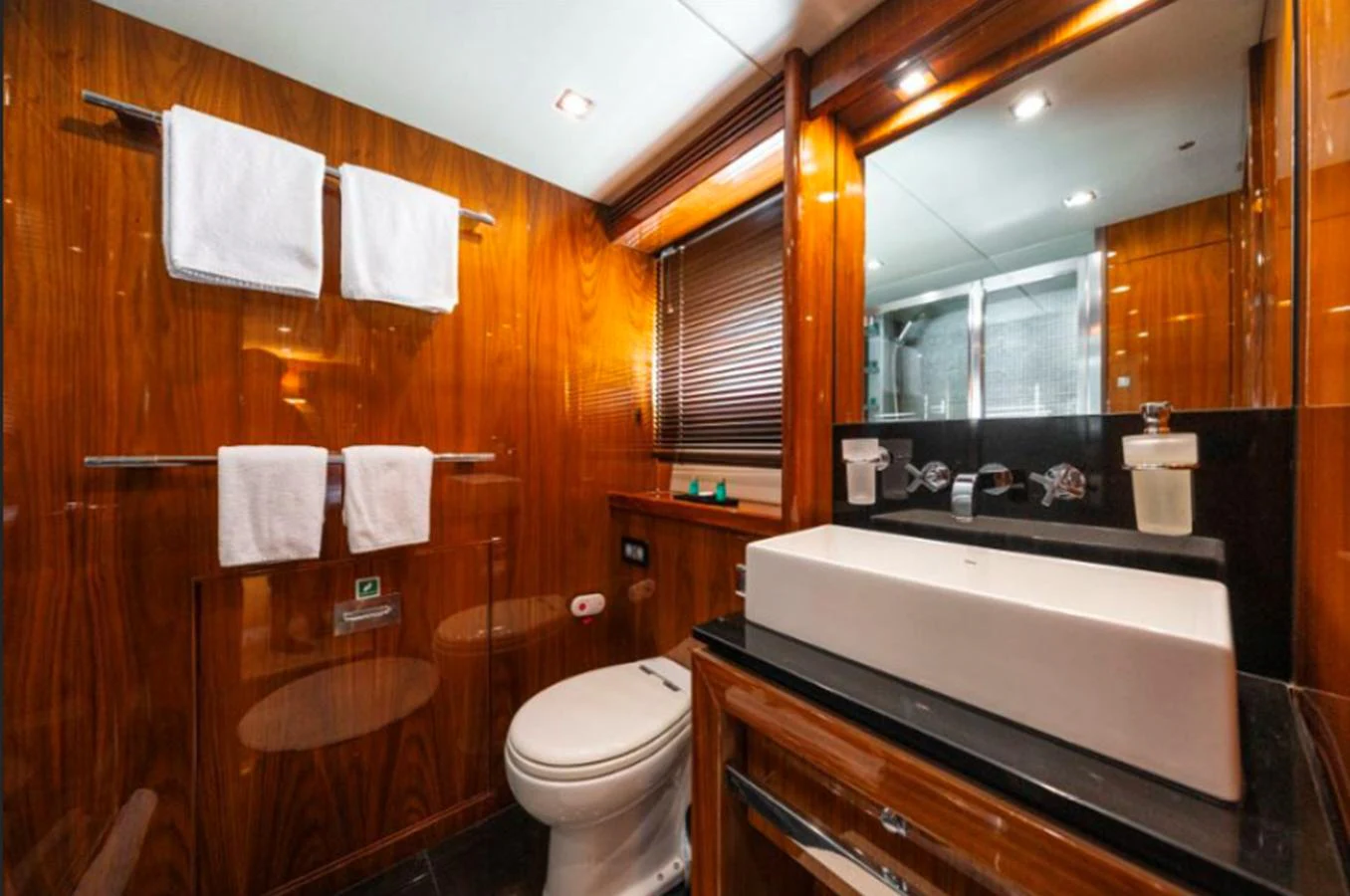 The yacht's bathroom features elegant wood paneling, a modern sink, and luxurious amenities. aboard ARAGO Yacht for Sale