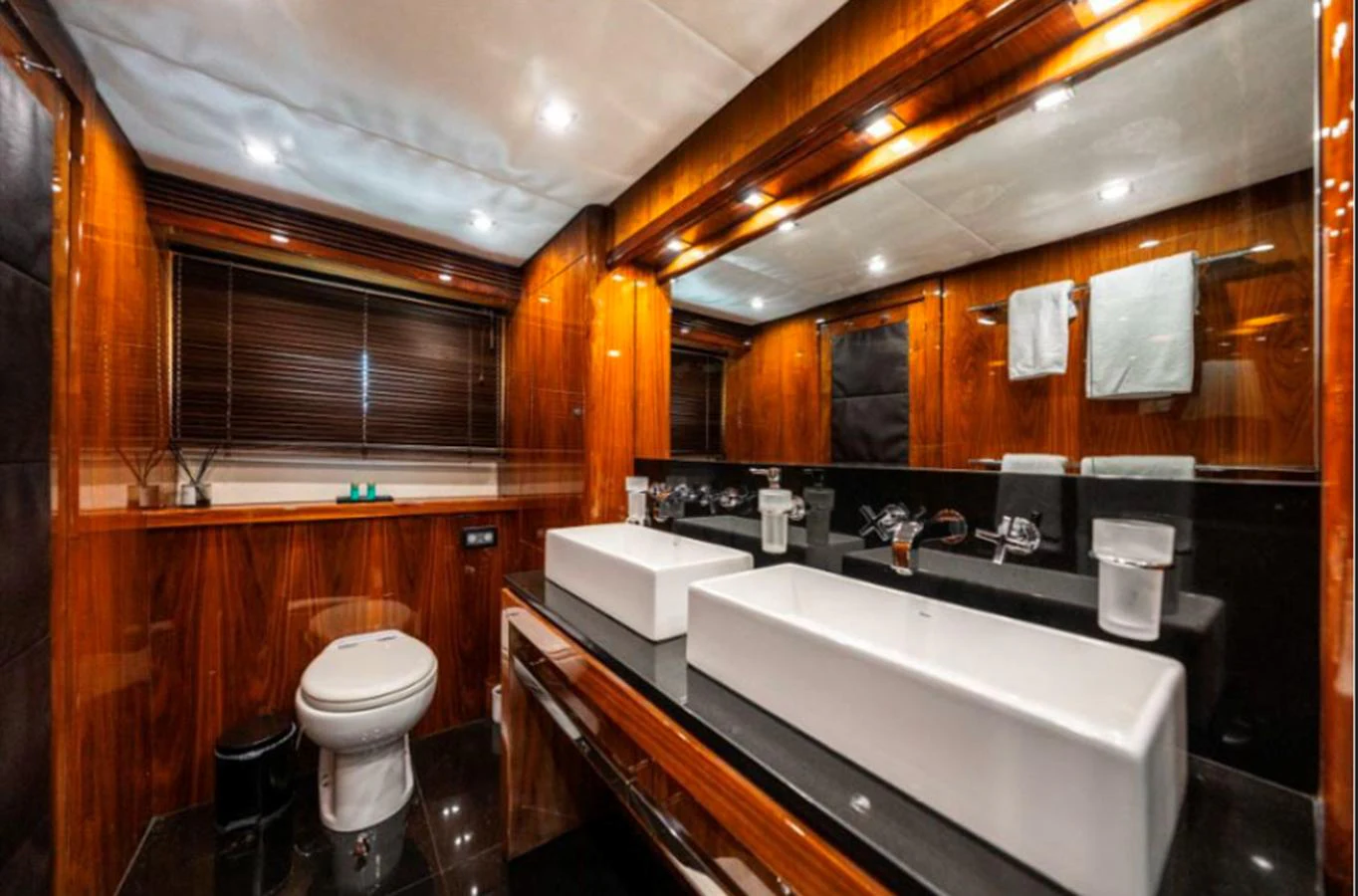 The yacht's bathroom features luxurious wood paneling, dual sinks, and modern fixtures. aboard ARAGO Yacht for Sale