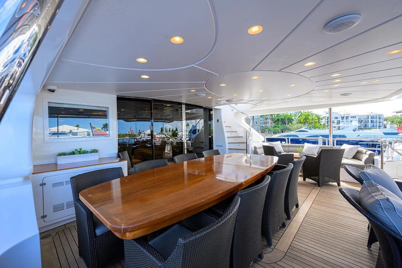 The aft deck features a spacious dining area with a polished wooden table and comfortable wicker chairs. aboard BENETTI CLASSIC Yacht for Sale