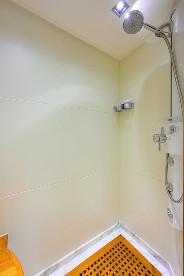 A sleek and modern yacht shower with a rainfall showerhead and wooden floor mat. aboard BENETTI CLASSIC Yacht for Sale